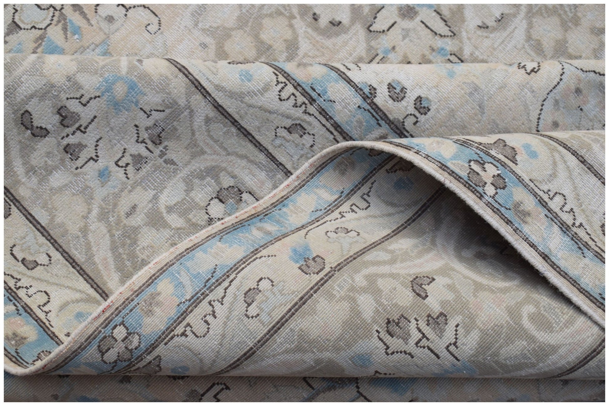 A vintage Persian Kerman rug featuring a soft floral pattern in blue and beige tones.