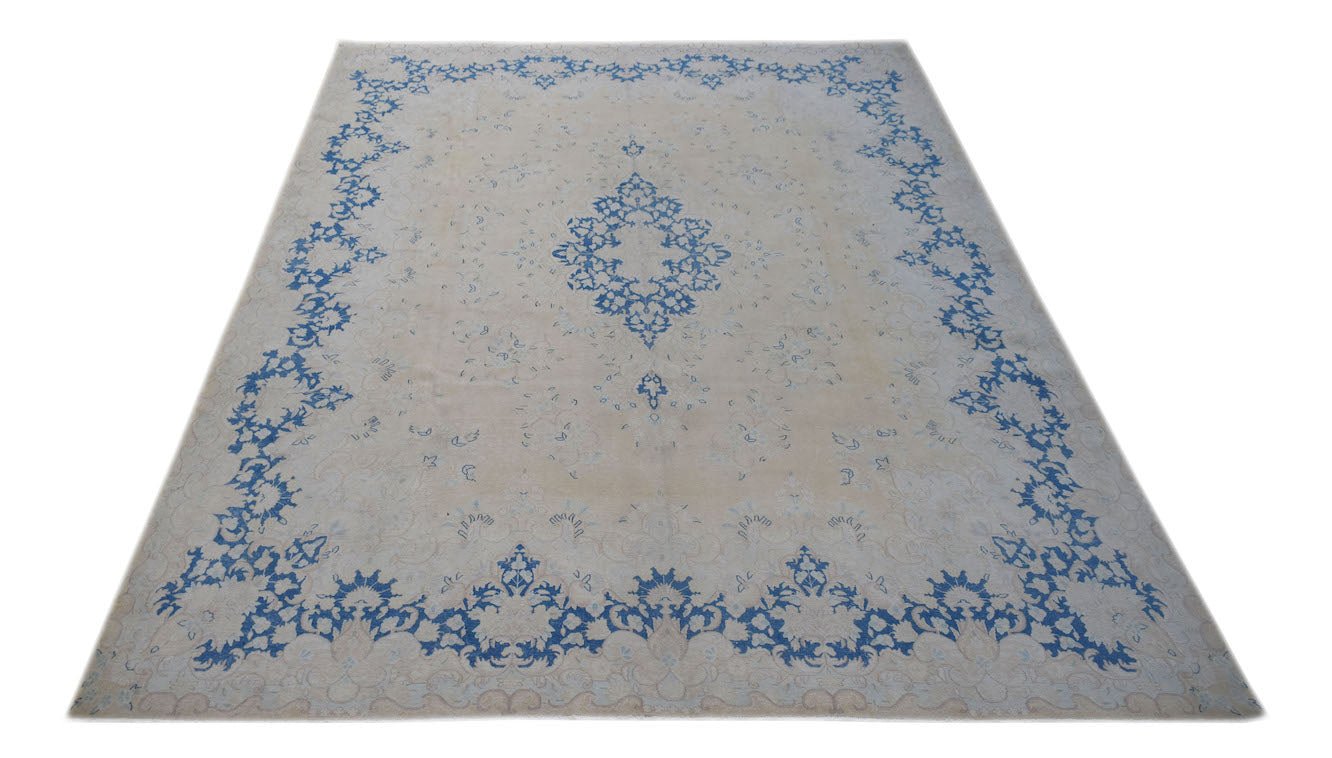 A vintage Persian Kerman rug featuring a central blue floral medallion on a cream field.