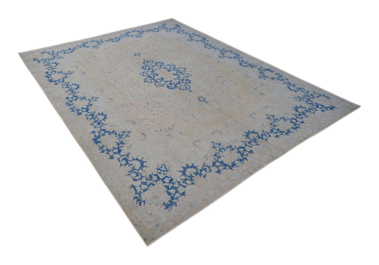 A vintage Persian Kerman rug featuring a central medallion and blue floral motifs on a beige field.