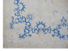 A vintage Persian Kerman rug featuring intricate blue floral patterns on a beige background.