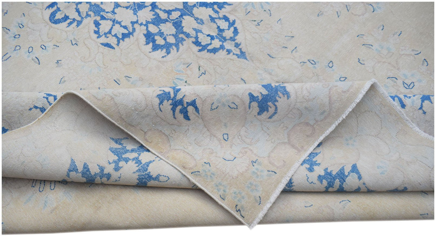 A vintage Persian Kerman rug featuring a blue floral medallion pattern on a cream background.