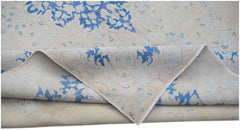 A vintage Persian Kerman rug featuring a blue floral medallion pattern on a cream background.