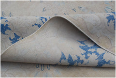 A vintage Persian Kerman rug featuring a blue floral pattern on a beige background.