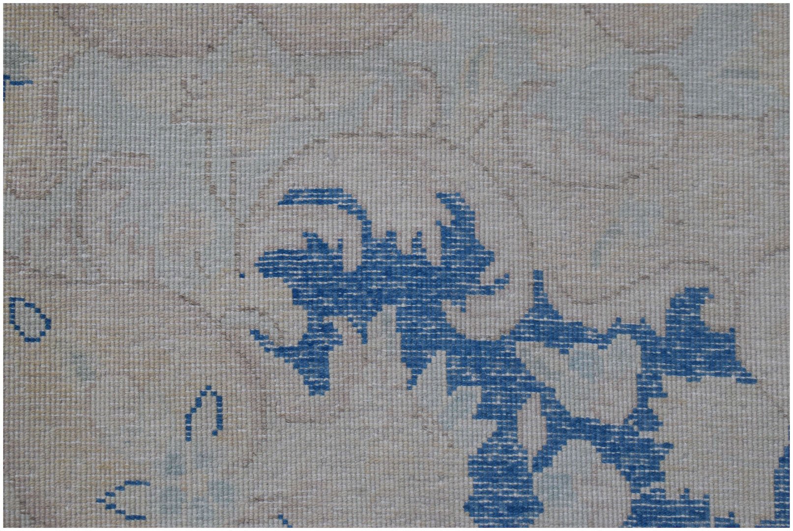 A close-up of a vintage Persian Kerman rug featuring intricate blue floral patterns on a beige base.