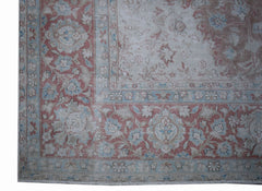 A vintage Persian Kerman rug featuring a faded floral pattern in soft pink, blue, and beige tones.
