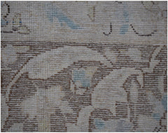 A close-up of a vintage Persian Kerman rug featuring intricate floral patterns in muted tones.