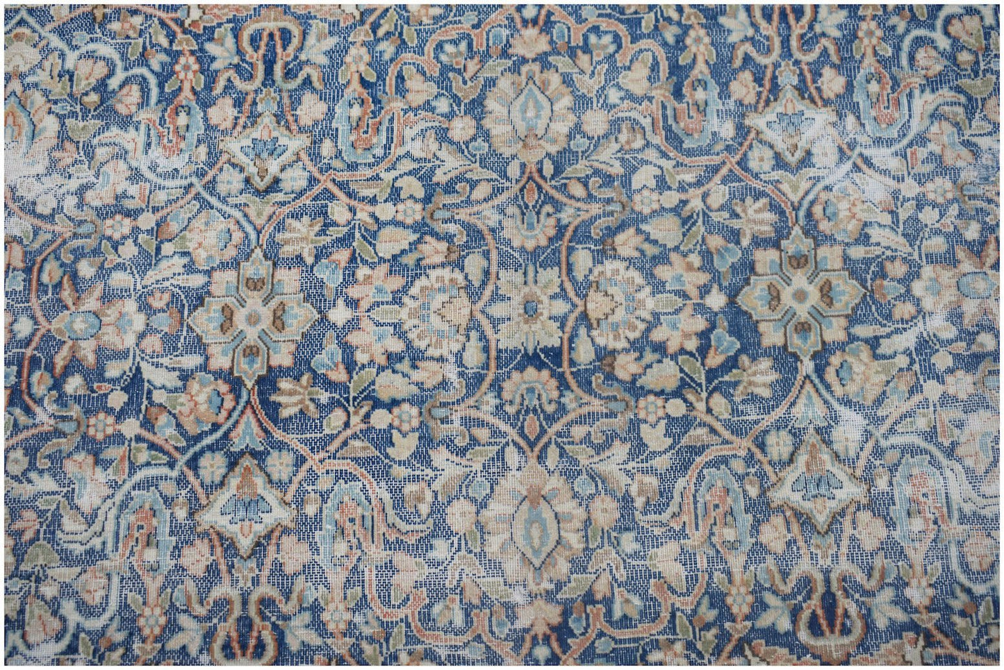 A vintage Persian Kerman rug featuring an intricate blue floral pattern with a central medallion.