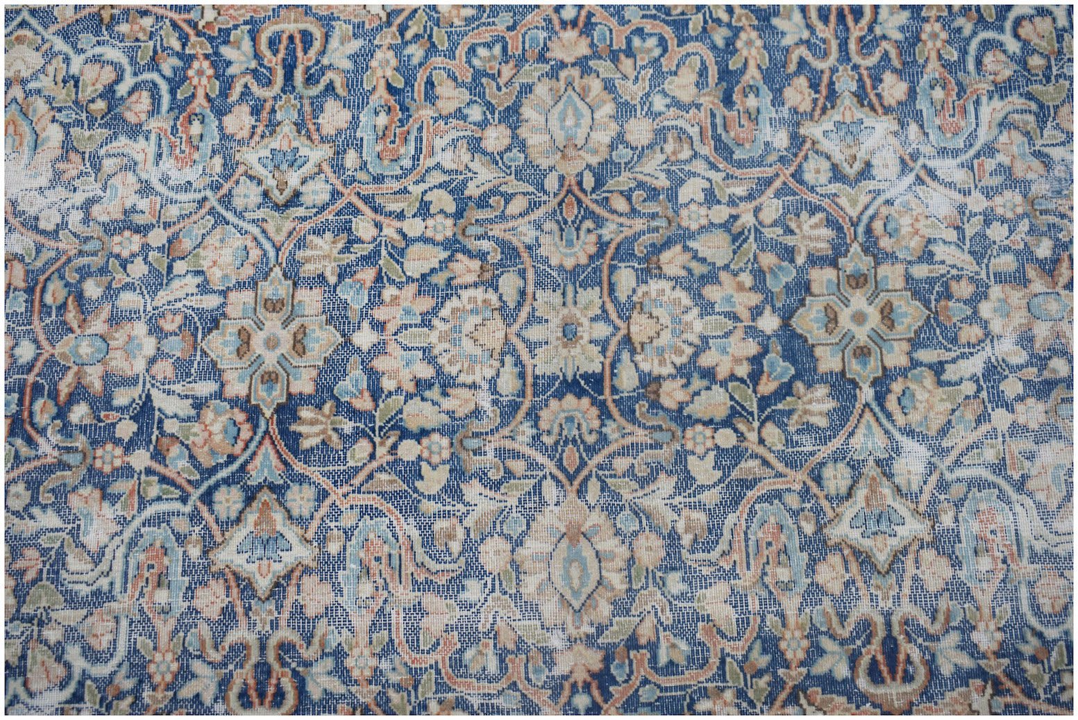 A vintage Persian Kerman rug featuring an intricate blue floral pattern with a central medallion.