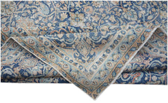 A vintage Persian Kerman rug featuring an intricate blue and beige floral medallion pattern.