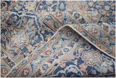 A vintage Persian Kerman rug featuring an intricate floral medallion design in blue and peach tones.