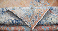 A vintage Persian Kerman rug featuring a floral pattern in shades of orange, blue, and cream.