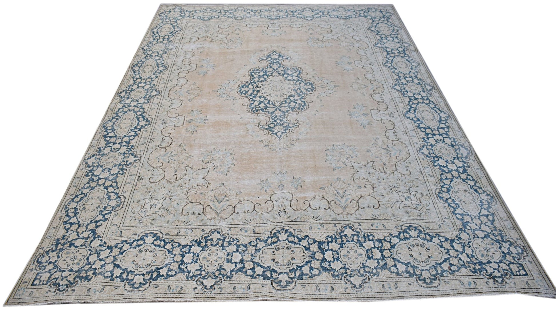 A vintage Persian Kerman rug featuring a central blue medallion on a soft beige floral field.