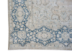 A vintage Persian Kerman rug featuring a blue and cream floral pattern with a central medallion.
