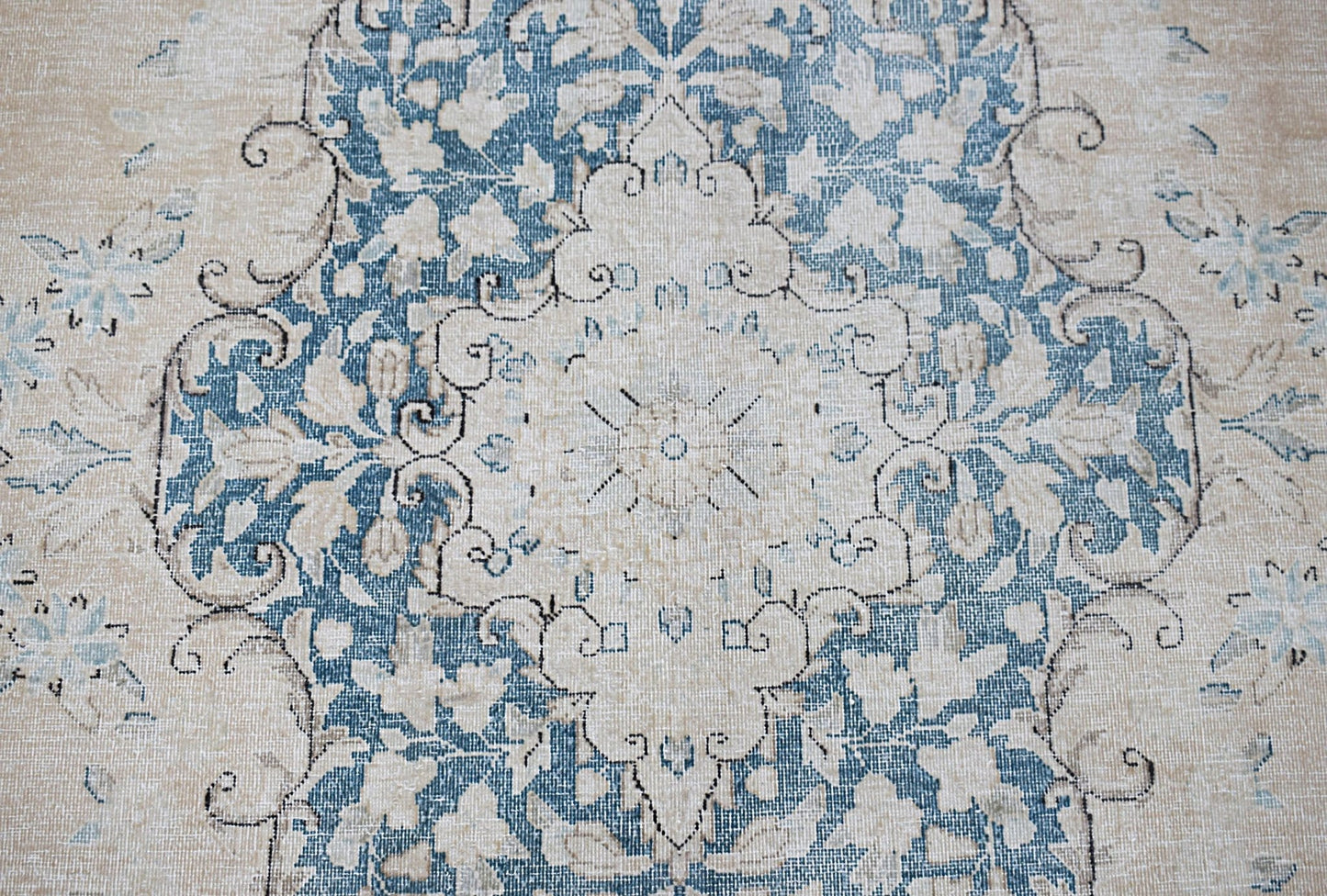 A vintage Persian Kerman rug featuring a central floral medallion in blue and cream tones.