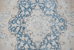 A vintage Persian Kerman rug featuring a central floral medallion in blue and cream tones.