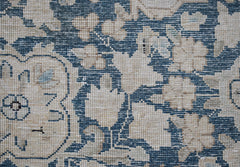 A close-up of a vintage Persian Kerman rug featuring intricate blue and cream floral patterns.