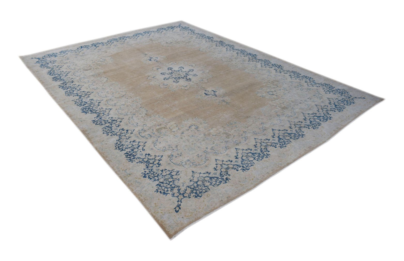A vintage Persian Kerman rug featuring a central medallion and blue floral border on a tan field.