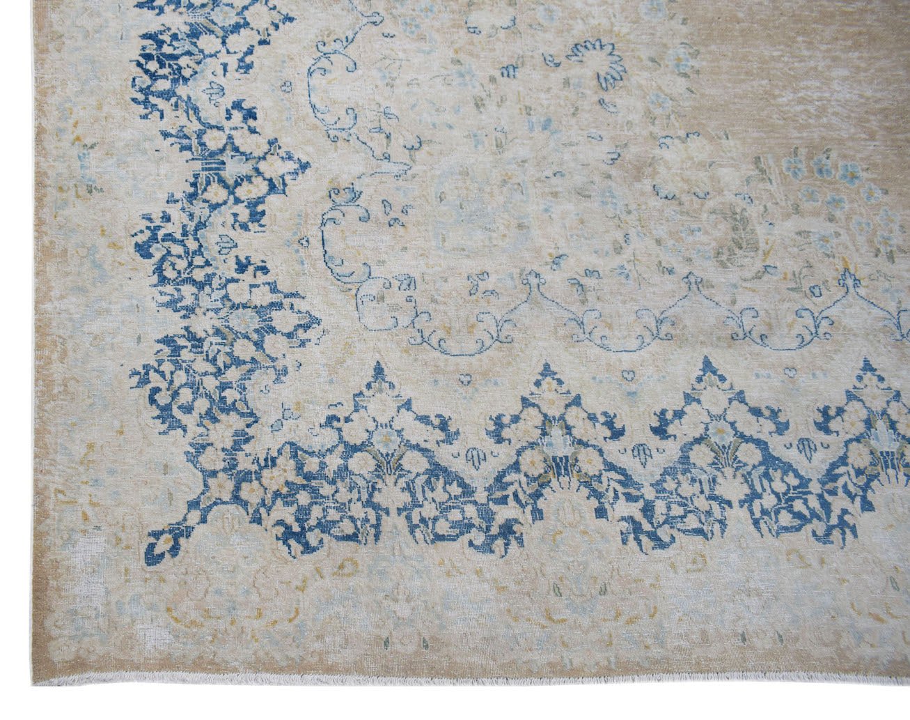 A vintage Persian Kerman rug featuring a blue floral medallion pattern on a beige background.