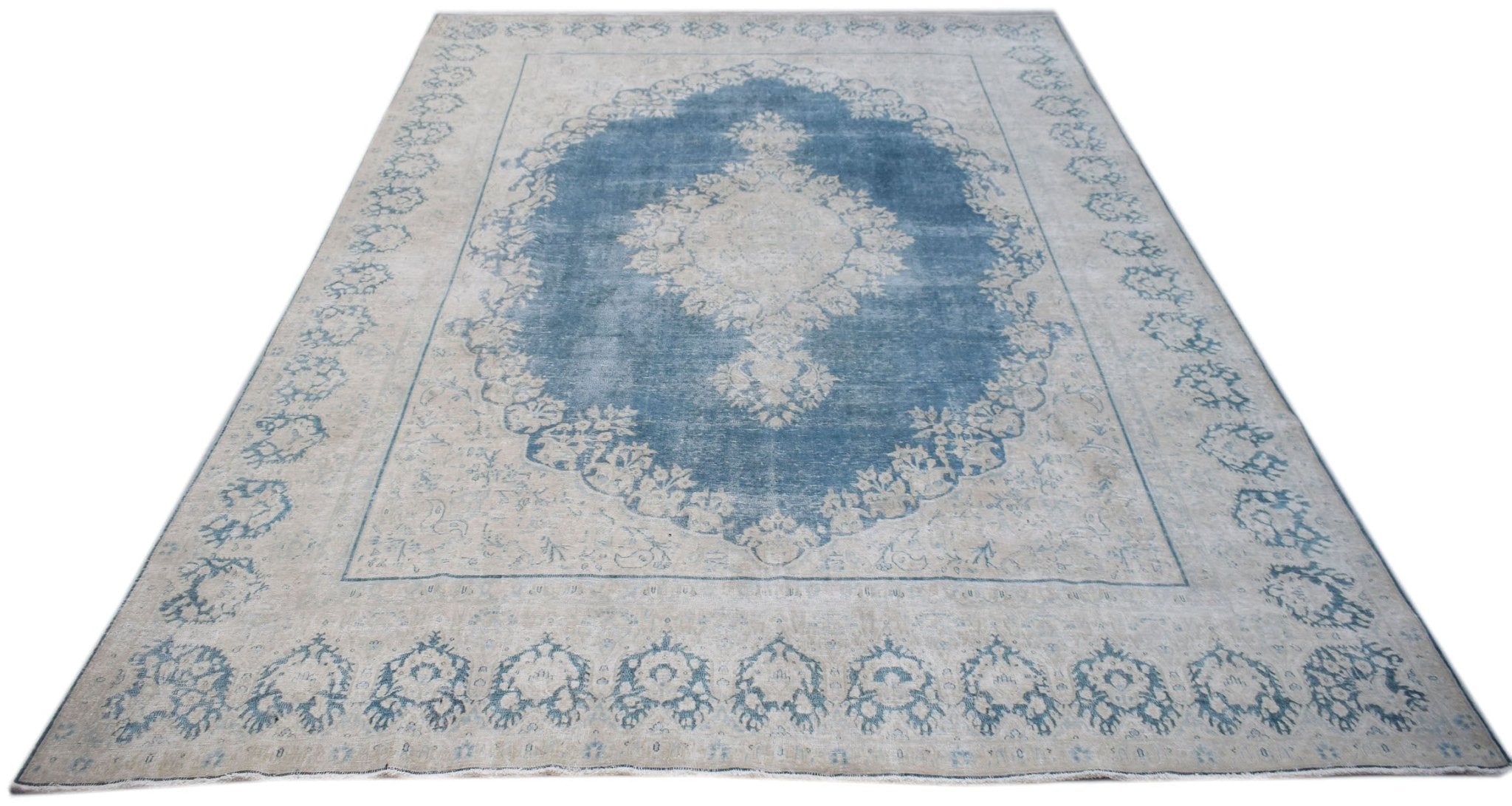 A vintage Persian Kerman rug featuring a central medallion and floral motifs in blue and cream.