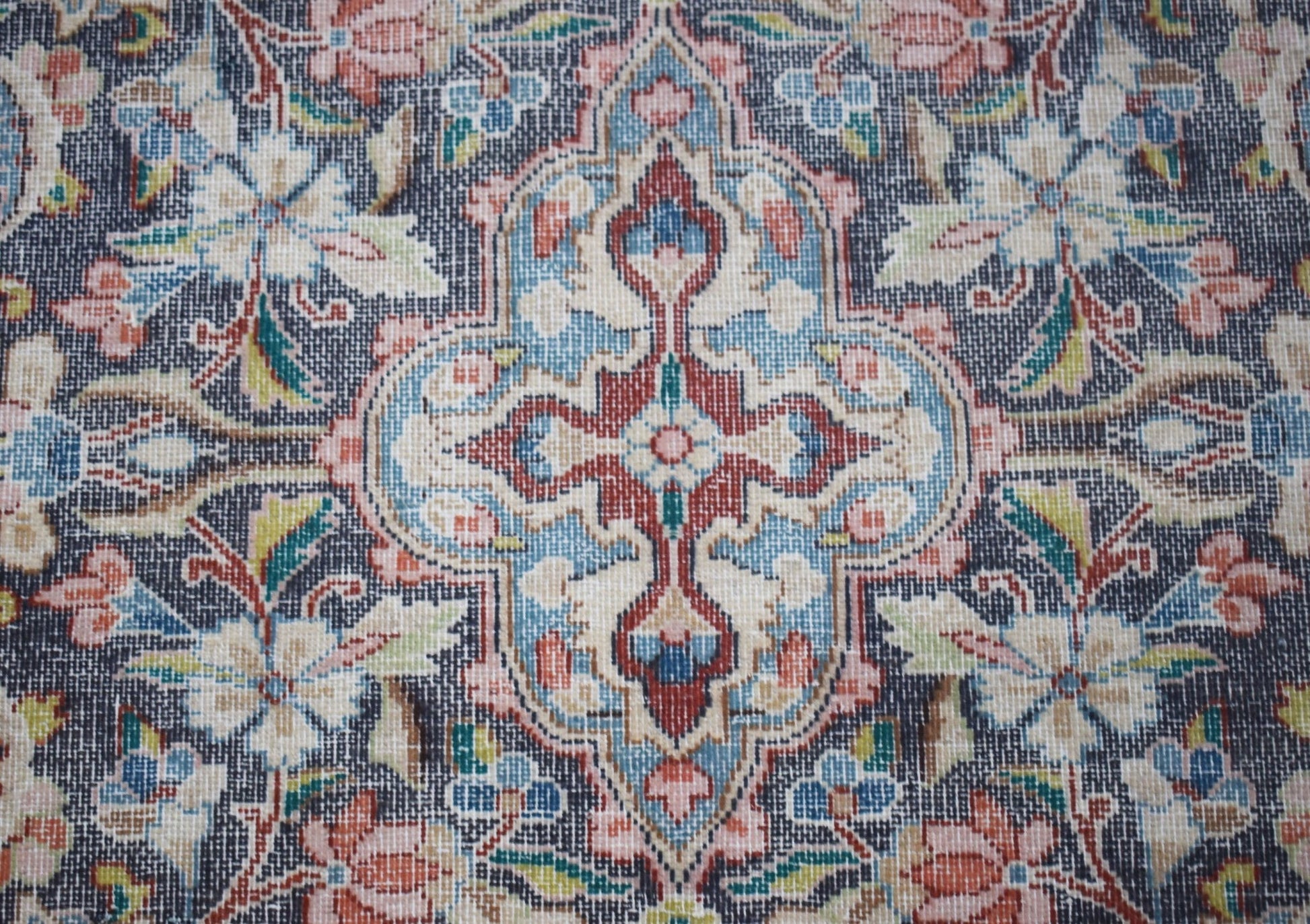 A vintage Persian Kerman rug featuring an intricate floral medallion in blue, red, and cream tones.