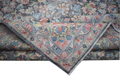 A vintage Persian Kerman rug featuring an intricate floral pattern and a folded corner.