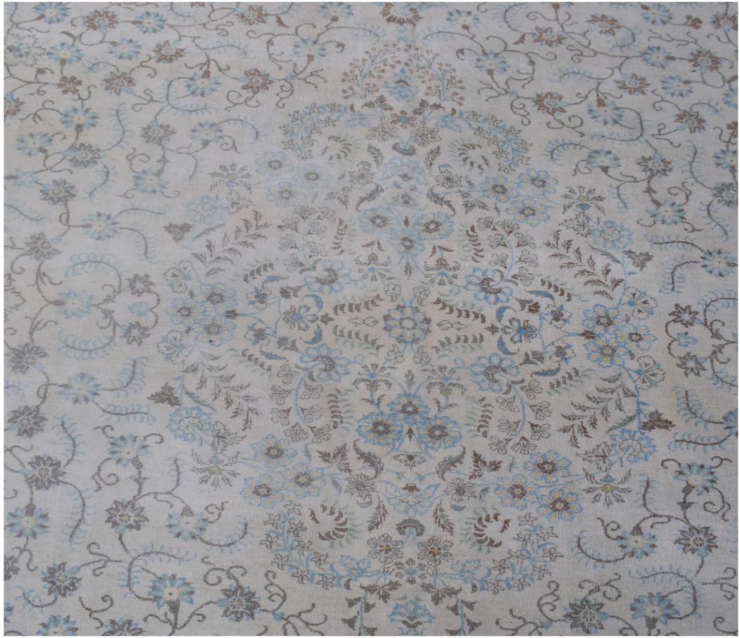 A vintage Persian Kerman rug featuring an intricate floral medallion in soft blue and brown tones.