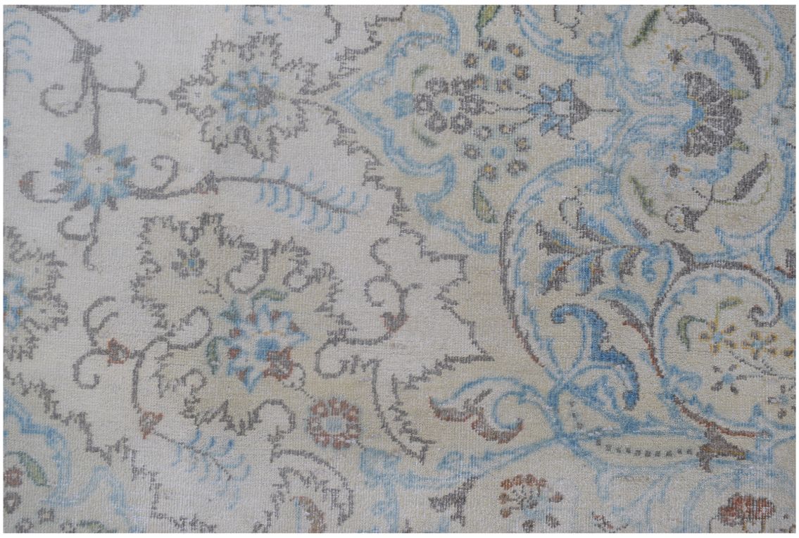 A vintage Persian Kerman rug featuring intricate floral patterns in soft blue and beige tones.