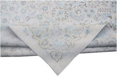 A vintage Persian Kerman rug featuring a light cream background with intricate blue floral patterns.