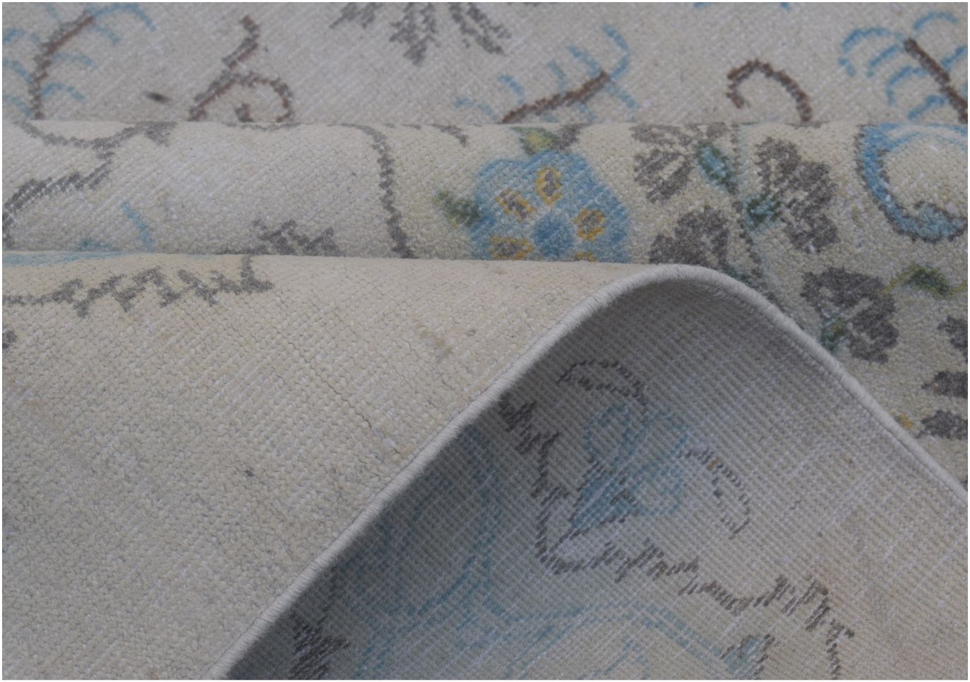 A close-up of a vintage Persian Kerman rug featuring a floral pattern in blue and grey tones.