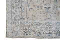 A vintage Persian Kerman rug featuring intricate floral patterns in soft blue and beige tones.