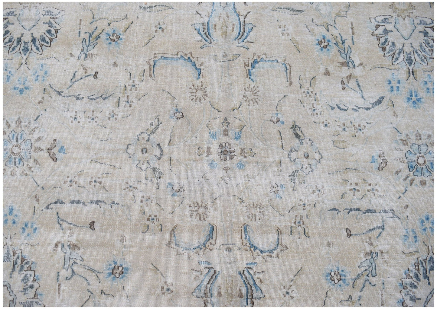 A vintage Persian Kerman rug featuring a faded floral medallion pattern in blue and beige tones.