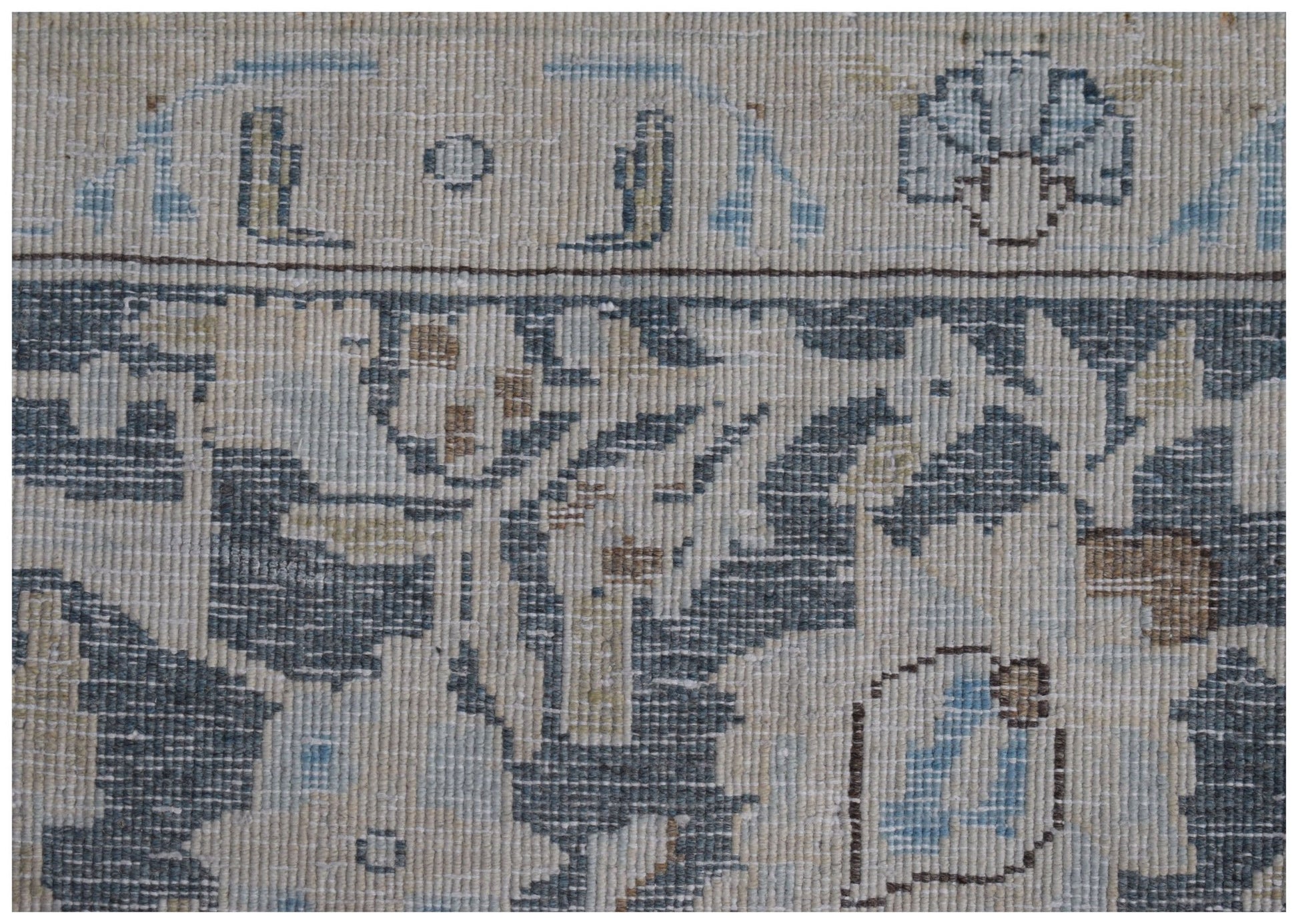 A close-up of a vintage Persian Kerman rug featuring intricate floral patterns in blue and beige.