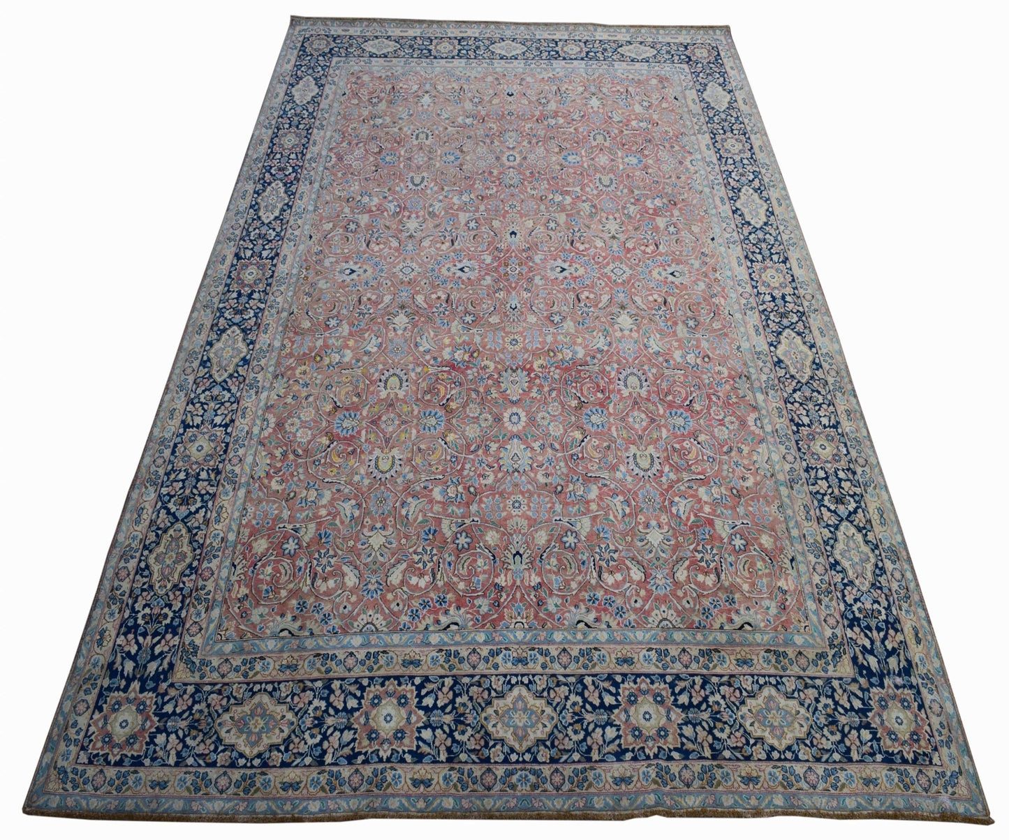 A vintage Persian Kerman rug featuring an intricate floral pattern in pink and blue tones.
