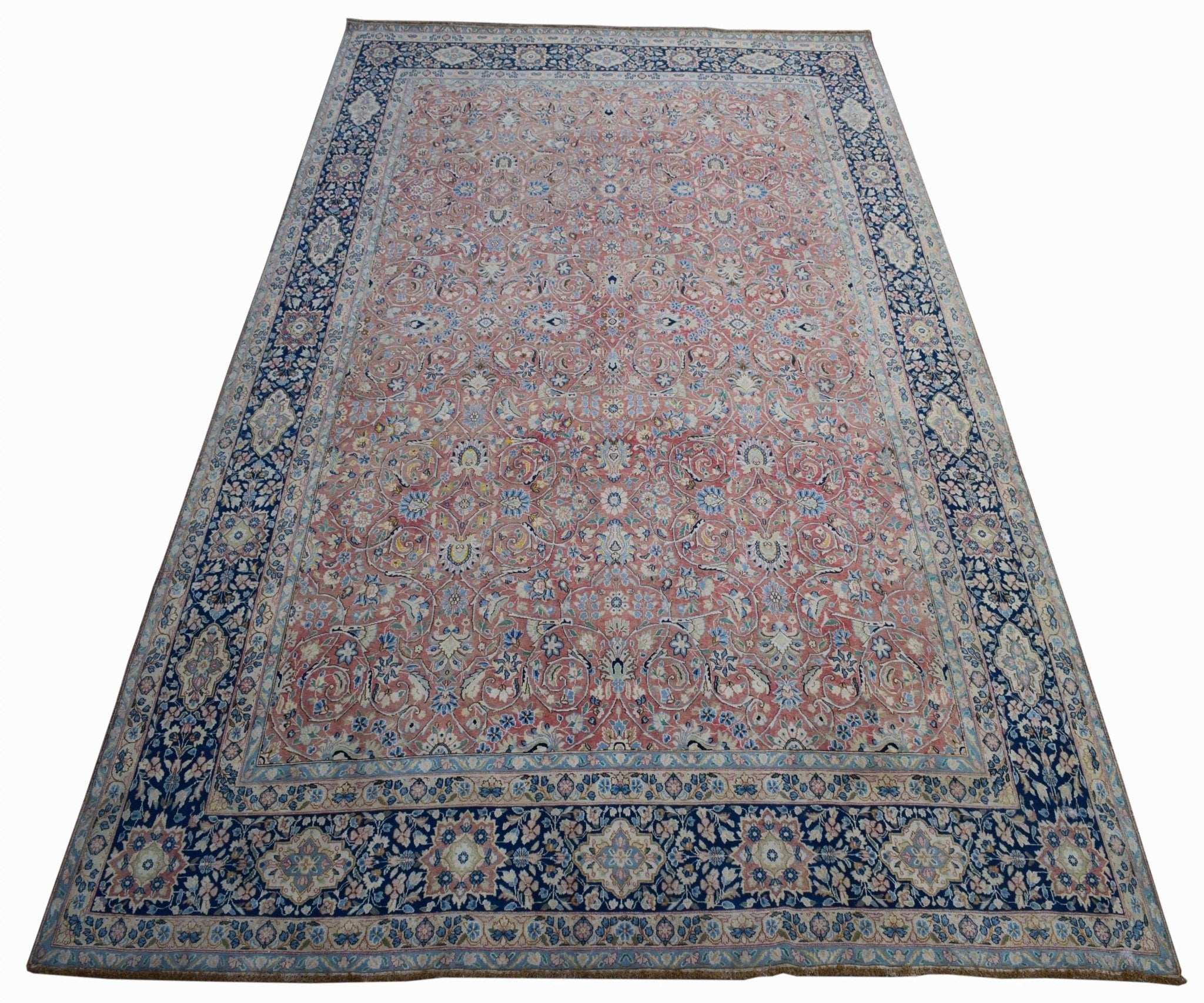 A vintage Persian Kerman rug featuring an intricate floral pattern in pink and blue tones.