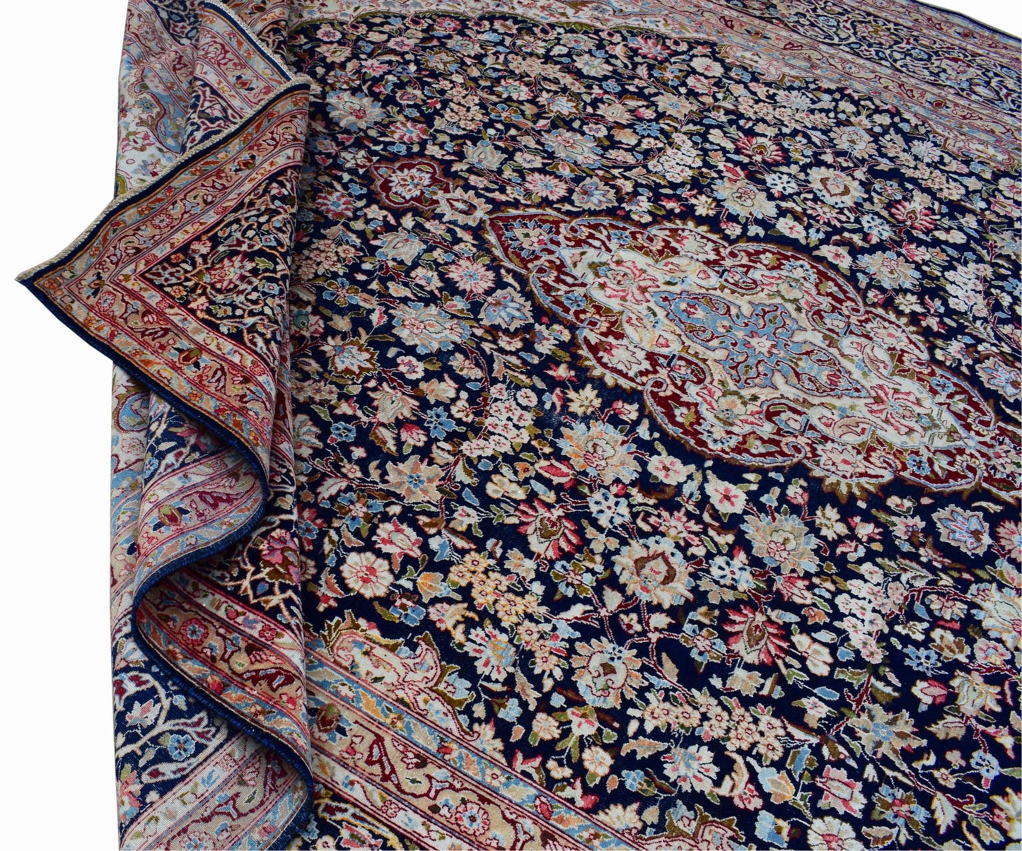 A vintage Persian Kerman rug featuring a dark blue field with a central floral medallion.