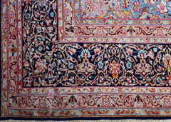 A vintage Persian Kerman rug featuring an intricate floral pattern with a deep blue border.