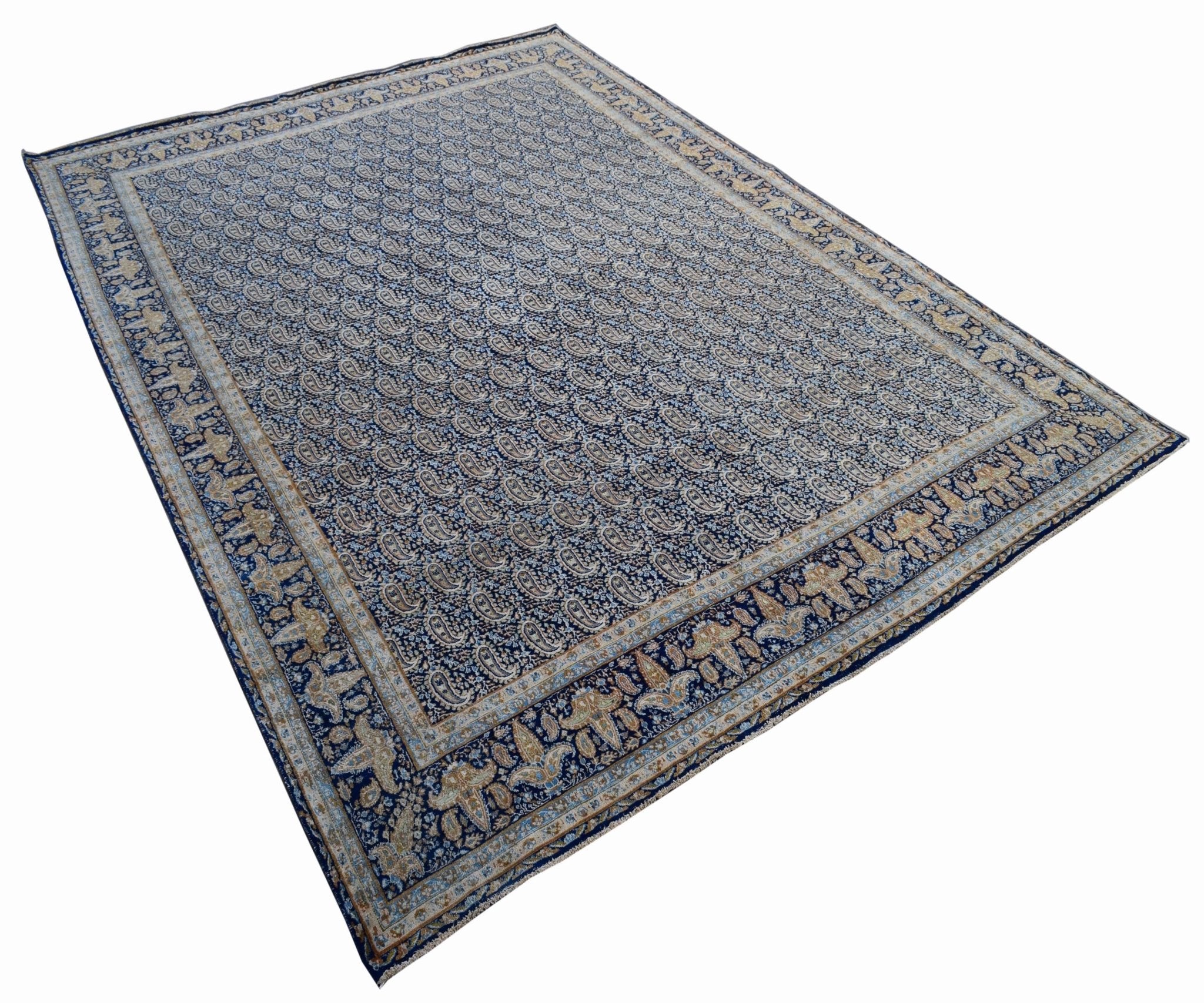 A vintage Persian Kerman rug featuring an intricate blue field with a repeating paisley pattern.