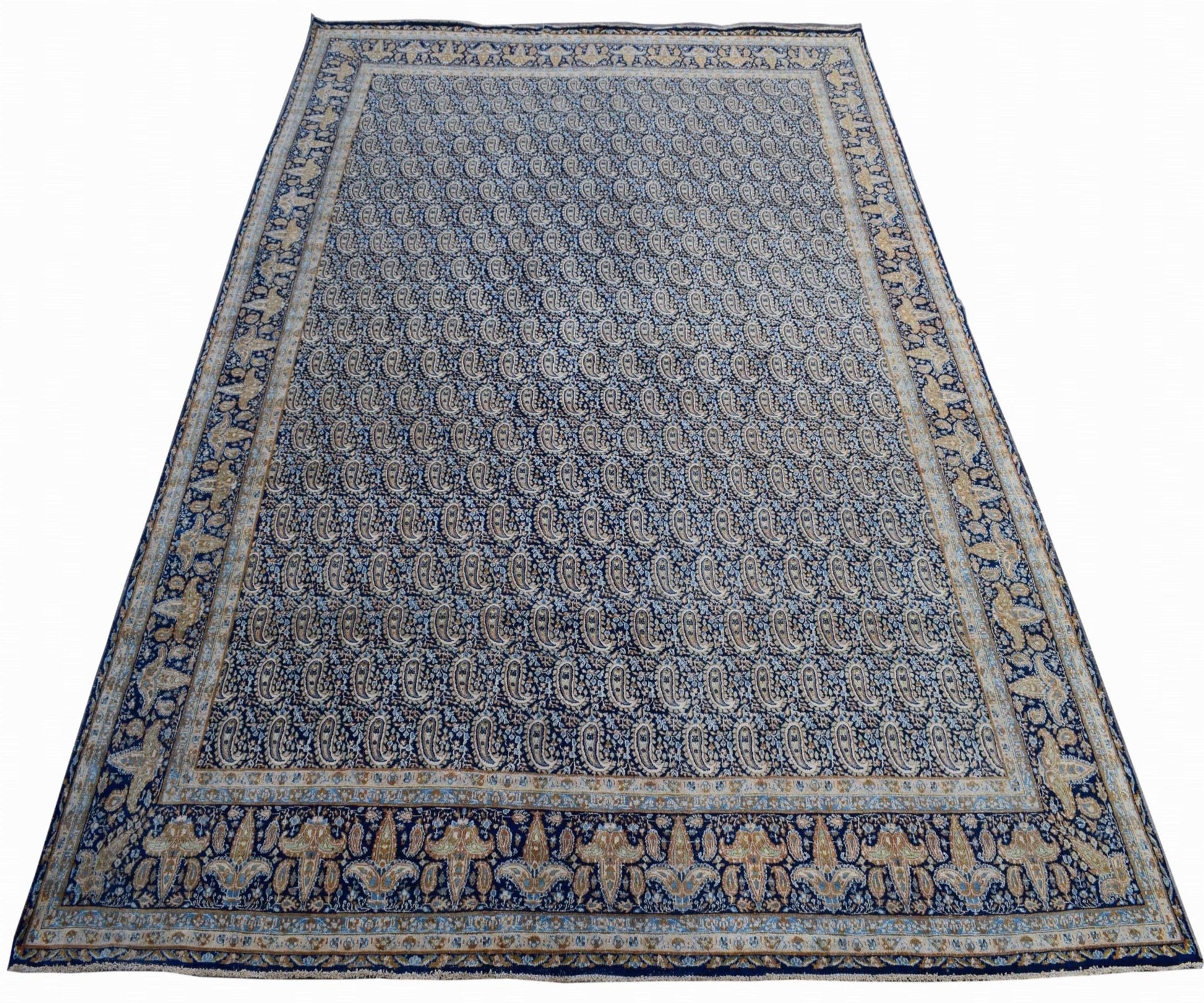 A vintage Persian Kerman rug featuring an intricate blue paisley pattern and floral borders.