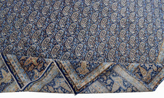 A vintage Persian Kerman rug featuring a dense blue paisley pattern and a decorative border.