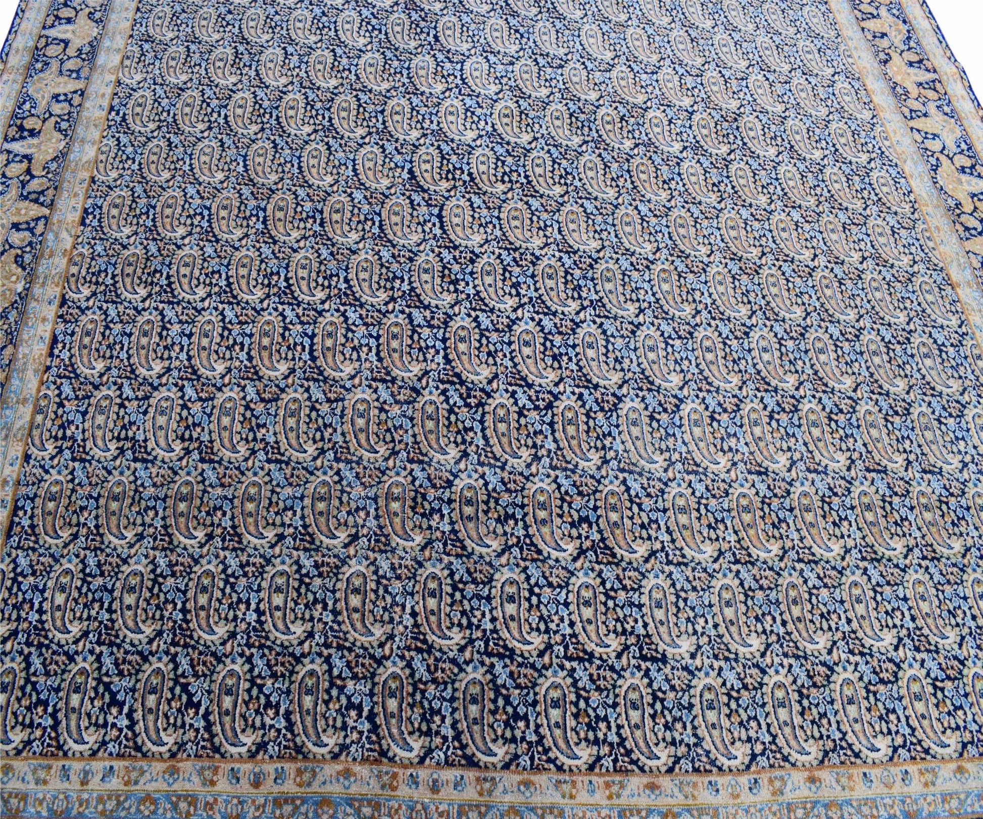 A vintage Persian Kerman rug featuring an intricate blue field with a repeating paisley pattern.