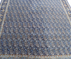 A vintage Persian Kerman rug featuring an intricate blue field with a repeating paisley pattern.