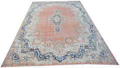 A vintage Persian Kerman rug featuring a central medallion and floral motifs in blue and peach.
