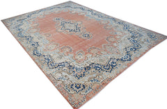 A vintage Persian Kerman rug featuring a central medallion and floral motifs in blue and peach.