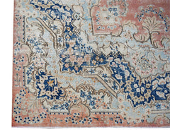 A vintage Persian Kerman rug featuring intricate floral patterns in blue, cream, and soft pink.