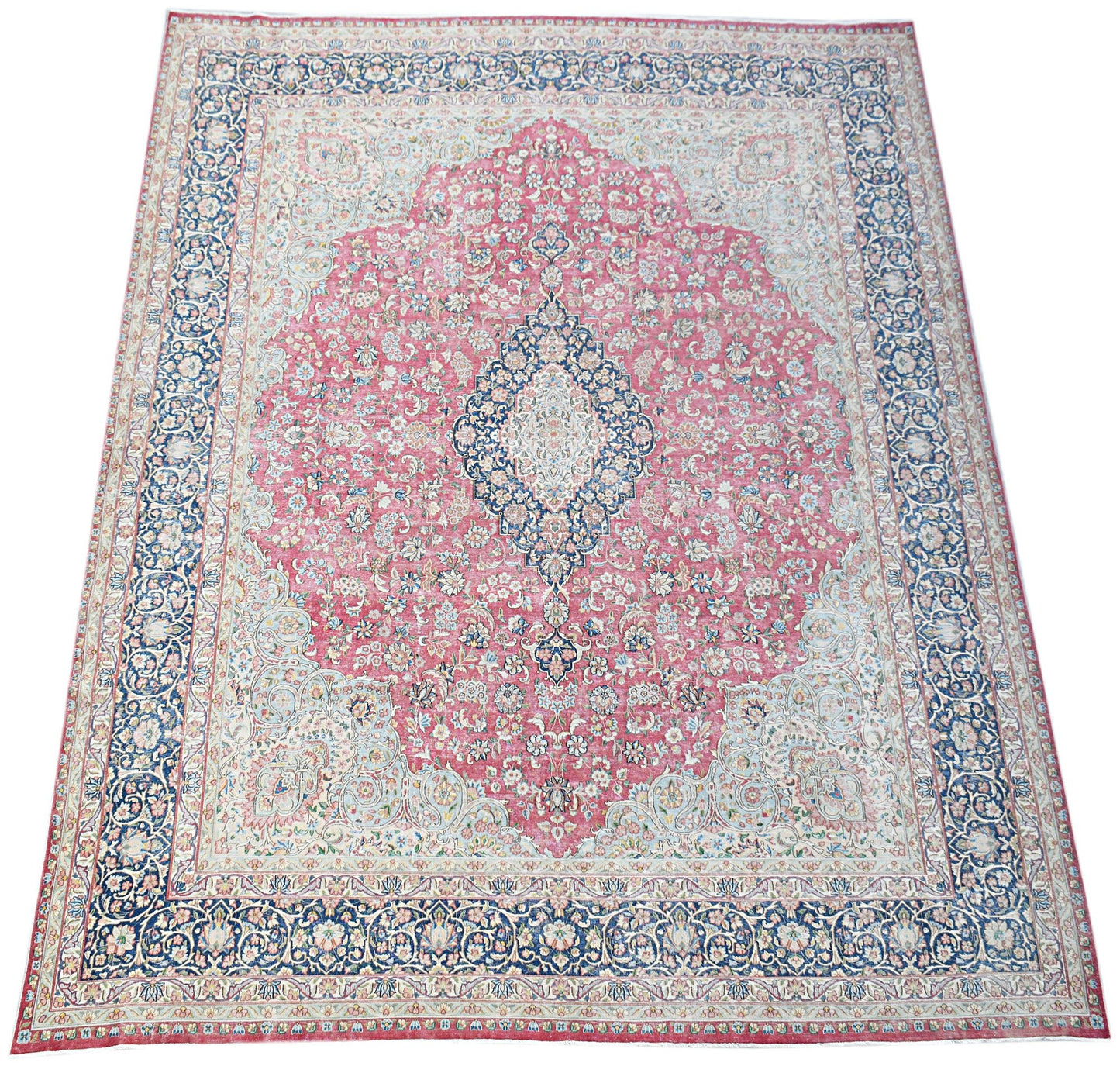A vintage Persian Kerman rug featuring a central medallion and intricate floral patterns in pink.