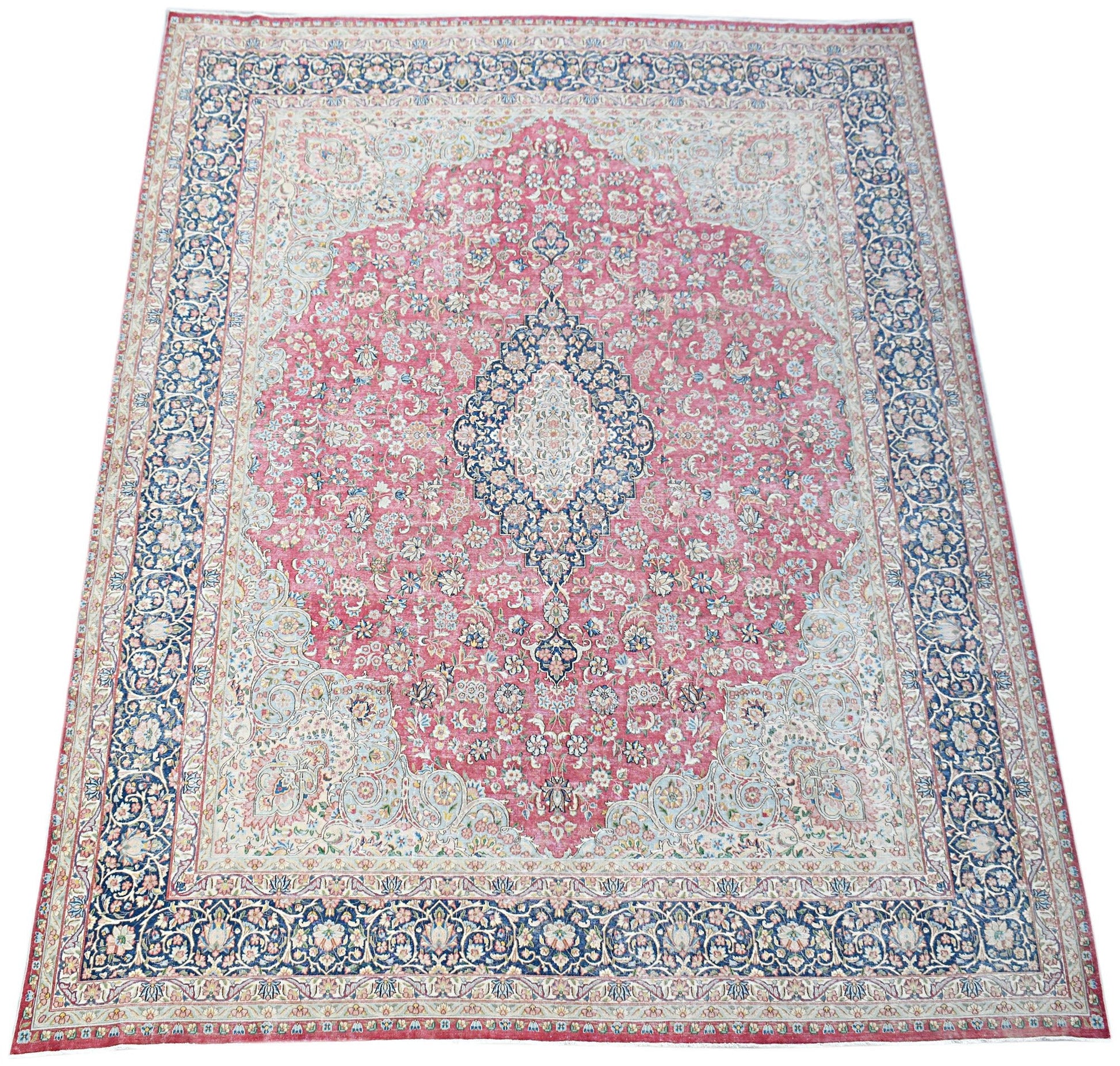 A vintage Persian Kerman rug featuring a central medallion and intricate floral patterns in pink.