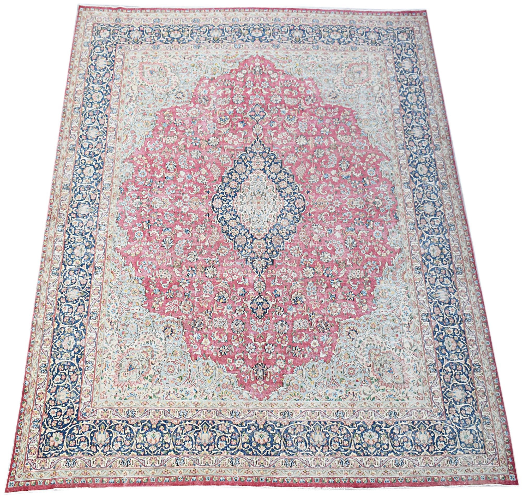 A vintage Persian Kerman rug featuring a central medallion and intricate floral patterns in pink.