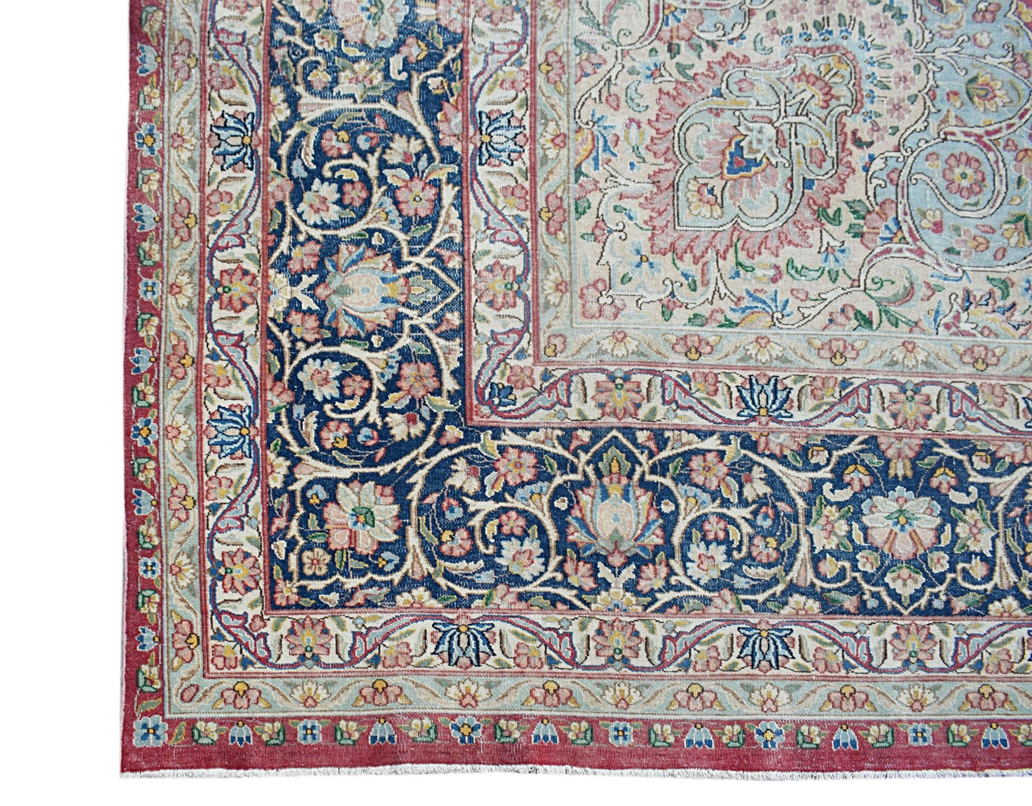 A vintage Persian Kerman rug featuring an intricate floral pattern with a deep blue border.