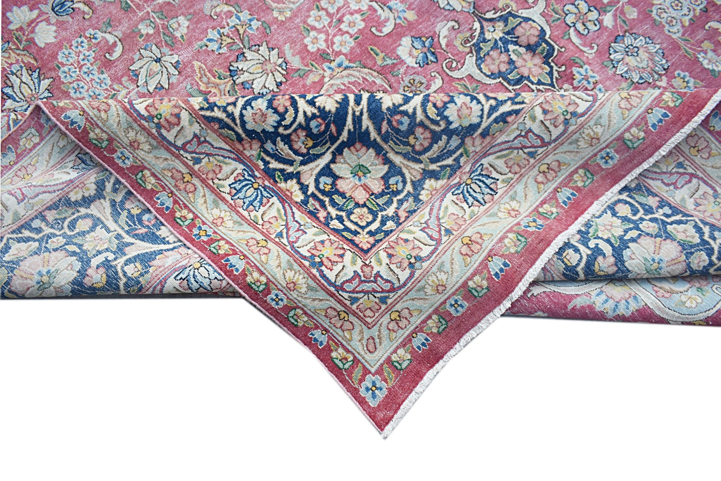 A vintage Persian Kerman rug featuring a floral medallion design in shades of pink and blue.