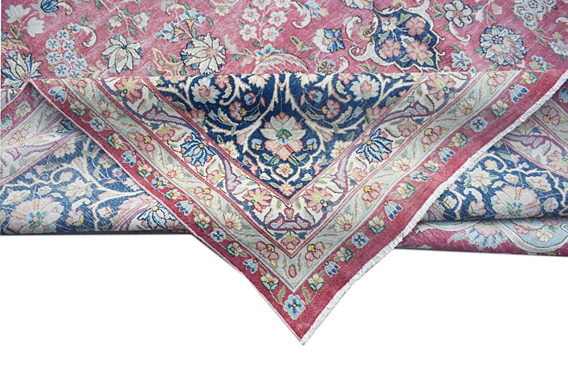 A vintage Persian Kerman rug featuring a floral medallion design in shades of pink and blue.